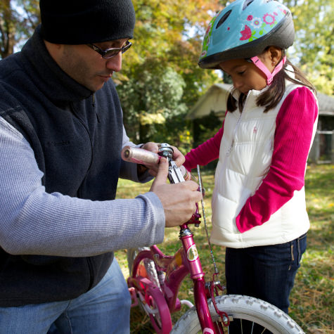 Man using a wave to fix a young girl's bike
